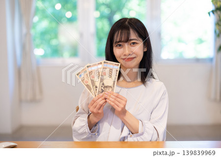 3枚の1万円札を手に微笑む日本人の若い女性 139839969