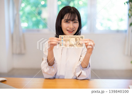 1万円札を手に微笑む日本人の若い女性 1万円札を手に微笑む日本人の若い女性 139840100