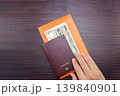 Man's hand holding international passport on brown dark wooden table. 139840901