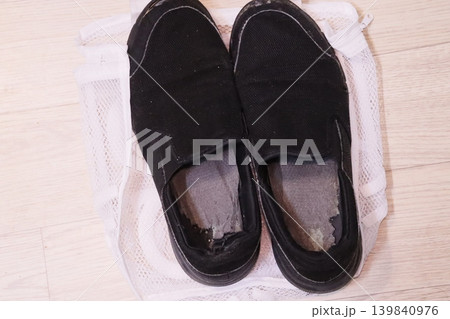 Worn Black Slip-On Shoes on Mesh Bag Worn Black Slip-On Shoes on Mesh Bag 139840976