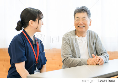 デイサービス,老人ホームにいる高齢者男性と介護福祉士,ヘルパーの女性 139841068
