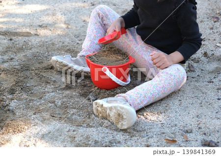 公園の砂場で赤い砂場セットで遊ぶ女の子 公園の砂場で赤い砂場セットで遊ぶ女の子 139841369