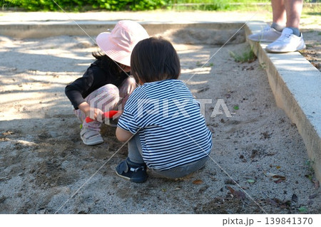 公園の砂場で仲良く遊ぶ幼児2人と見守る親 公園の砂場で仲良く遊ぶ幼児2人と見守る親 139841370