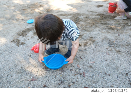 公園で青いふるいのおもちゃで遊ぶ子供 公園で青いふるいのおもちゃで遊ぶ子供 139841372
