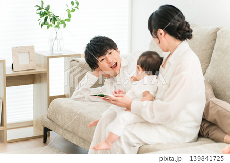 子供をあやすパパ,赤ちゃんに絵本を読む子育て世代のファミリー（育児,子育て,スキンシップ） 139841725