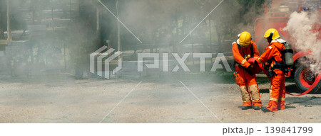 Firefighter Rescue training in fire fighting extinguisher. Firefighter fighting with flame using fire hose chemical water foam spray engine. Fireman wear hard hat, safety suit uniform for protection 139841799