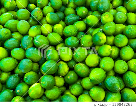 Limes are stacked in a grocery store during the day under bright lighting for shoppers to select and buy 139842265