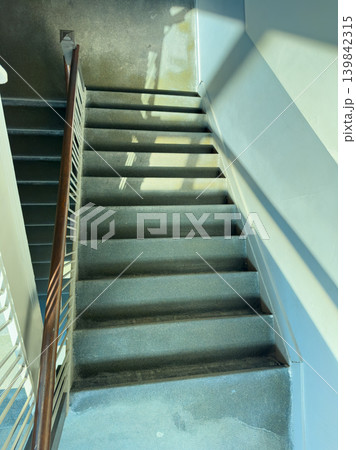 Stairs in a building with sunlight streaming down in the morning, highlighting each step and creating shadows on the wall Stairs in a building with sunlight streaming down in the morning, highlighting each step and creating shadows on the wall 139842315
