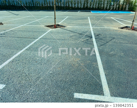 Empty parking lot with marked spaces and planned tree locations in a commercial area in daytime hours Empty parking lot with marked spaces and planned tree locations in a commercial area in daytime hours 139842351