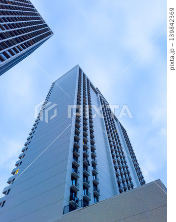 Tall building surrounded by other structures under a blue sky with some clouds in the late afternoon Tall building surrounded by other structures under a blue sky with some clouds in the late afternoon 139842369