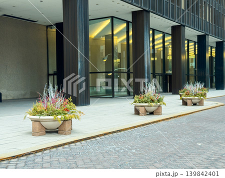 Planters display plants in front of building on city street during daytime with clear skies 139842401