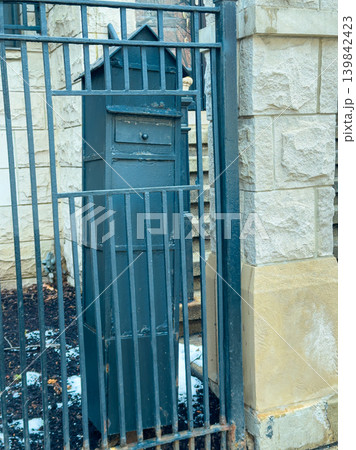 Mailbox stands outside a gated entrance near a stone building on a winter day in a quiet neighborhood Mailbox stands outside a gated entrance near a stone building on a winter day in a quiet neighborhood 139842423