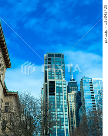 Modern buildings reach toward the blue sky in a busy city during the bright afternoon hours Modern buildings reach toward the blue sky in a busy city during the bright afternoon hours 139842429
