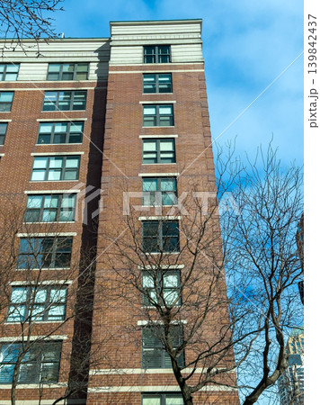 Building with brick exterior and clear sky seen from the ground level during daytime in an urban area 139842437