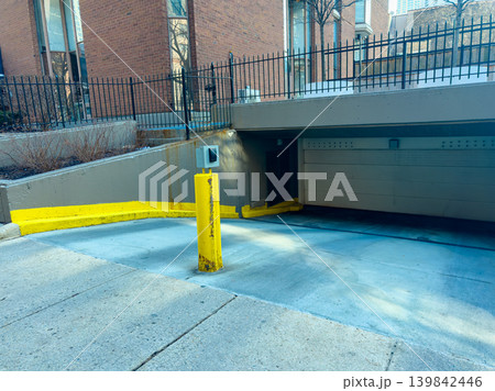 Parking area with entrance ramp leading to underground section located in a city setting during daylight hours 139842446