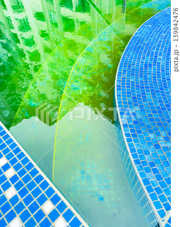 Water reflections show blue tiles and green hues in a pool area during midday in a residential complex Water reflections show blue tiles and green hues in a pool area during midday in a residential complex 139842476