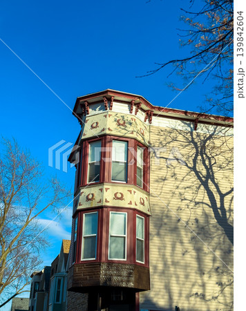 Bright day with clear skies highlighting a historical building with decorative details and unique architectural features in a city neighborhood during late afternoon Bright day with clear skies highlighting a historical building with decorative details and unique architectural features in a city neighborhood during late afternoon 139842604