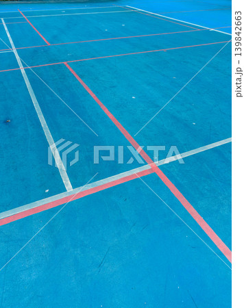 Bright blue sports court with clearly marked lines for tennis, badminton, and other activities during daytime hours in an urban setting Bright blue sports court with clearly marked lines for tennis, badminton, and other activities during daytime hours in an urban setting 139842663