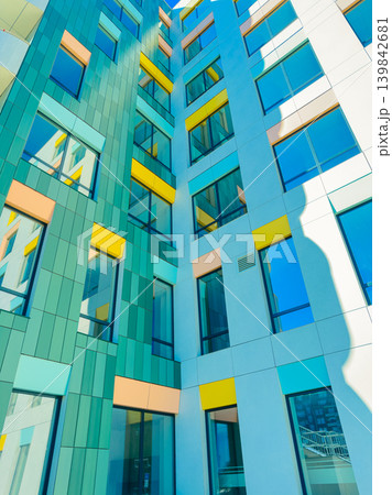 Modern building with colorful windows in urban area on a sunny day capturing sunlight and shadows Modern building with colorful windows in urban area on a sunny day capturing sunlight and shadows 139842681