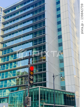 Building stands high in urban setting with red traffic light visible on a busy street during daytime Building stands high in urban setting with red traffic light visible on a busy street during daytime 139842739