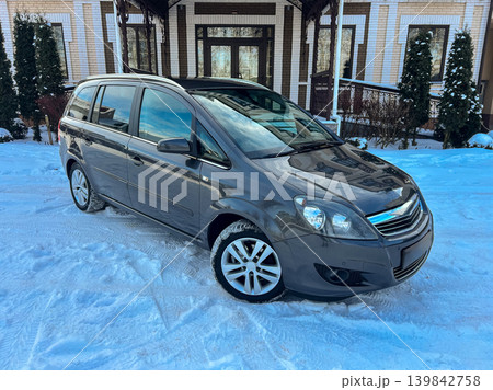 Car parked on snow-covered street in front of a house with large windows during the day in winter season Car parked on snow-covered street in front of a house with large windows during the day in winter season 139842758