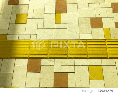 Yellow tactile paving on sidewalk in urban area designed for better accessibility while people walk along the street Yellow tactile paving on sidewalk in urban area designed for better accessibility while people walk along the street 139842791