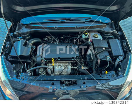 Car engine bay shows various parts and components in detail during daylight at a garage or parking area Car engine bay shows various parts and components in detail during daylight at a garage or parking area 139842814