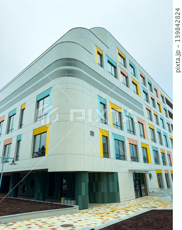 Modern building in an urban area showing colorful exterior design with large windows during a cloudy day 139842824