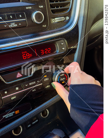 Driver adjusts temperature settings in car while parked at a location during the afternoon at 3:22 PM on a clear day Driver adjusts temperature settings in car while parked at a location during the afternoon at 3:22 PM on a clear day 139842878