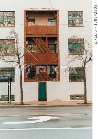 Stairs on a building with windows and trees near a street during daytime in an urban area 139842905
