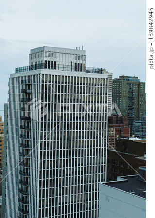 Tall building stands among other structures in a city skyline under cloudy skies during the day with a mixture of modern and older architecture 139842945