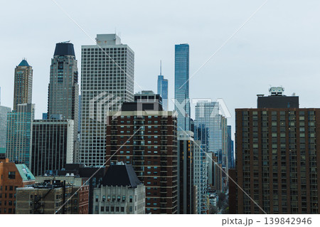 City skyline shows modern buildings against a gray sky in an urban area, with tall structures and a mix of architectural styles in view City skyline shows modern buildings against a gray sky in an urban area, with tall structures and a mix of architectural styles in view 139842946