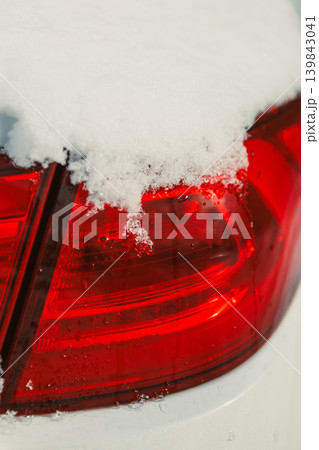 Snow covers the rear light of a parked car in a winter scene near a residential area during midday in January 139843041