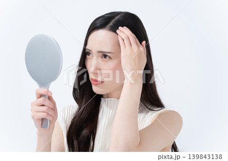 手鏡を見て髪の毛の生え際をチェックをする女性 139843138