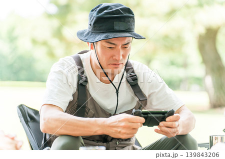 キャンプに来てゲームをする男性キャンパー 139843206