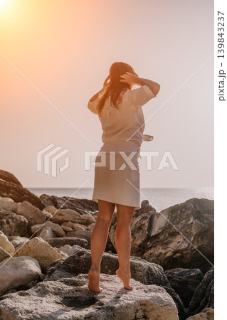 Woman sunset coast standing on rocky shore looking at sea with copy space for travel concept Woman sunset coast standing on rocky shore looking at sea with copy space for travel concept 139843237