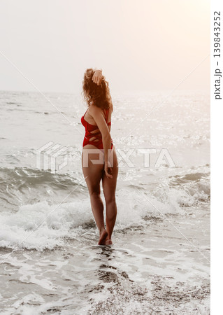 Woman beach swimsuit standing in ocean waves during sunset for a relaxing summer vacation concept 139843252
