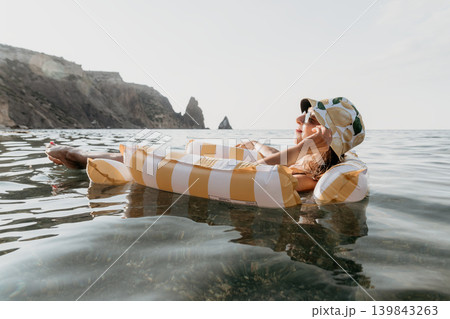 Woman, Beach, Inflatable Relaxing on Yellow Striped Raft in Ocean. Woman, Beach, Inflatable Relaxing on Yellow Striped Raft in Ocean. 139843263