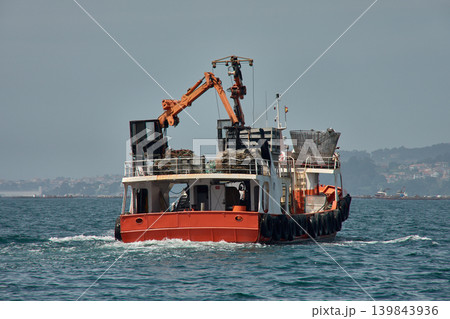 Traditional Galician mussel harvesting with an orange mussel boat off the coast of Vigo Traditional Galician mussel harvesting with an orange mussel boat off the coast of Vigo 139843936