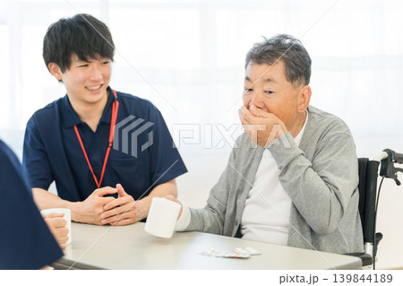 介護施設,老人ホームで薬を飲むシニア男性と介護職員の男性スタッフ 介護施設,老人ホームで薬を飲むシニア男性と介護職員の男性スタッフ 139844189