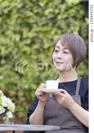 庭でガーデニングをしながらコーヒーを飲むシニア女性 庭でガーデニングをしながらコーヒーを飲むシニア女性 139844192