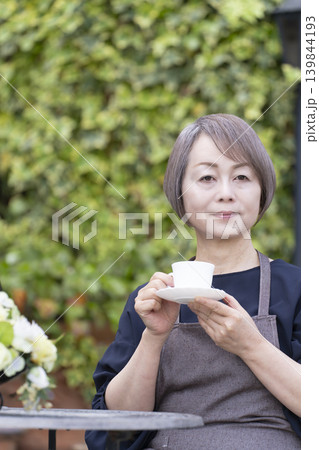 庭でガーデニングをしながらコーヒーを飲むシニア女性 139844193