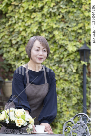 庭でガーデニングをしながらコーヒーを飲むシニア女性 庭でガーデニングをしながらコーヒーを飲むシニア女性 139844206