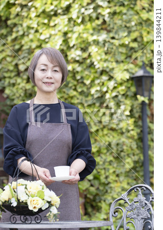 庭でガーデニングをしながらコーヒーを飲むシニア女性 139844211