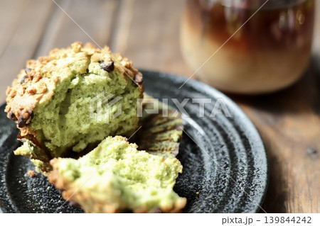 半分に割った抹茶チョコチップマフィンとアイスカフェオレ 139844242
