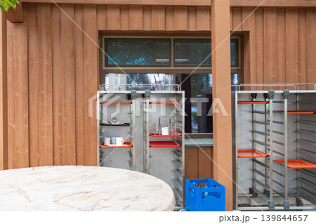 Backyard of a restaurant or warehouse featuring iron catering equipment, a round table in the foreground. Industrial domestic routine concept. Backyard of a restaurant or warehouse featuring iron catering equipment, a round table in the foreground. Industrial domestic routine concept. 139844657