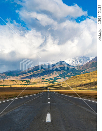 Breathtaking view of an open road leading to majestic mountains in Gorny Altay during a clear day with scattered clouds 139845132