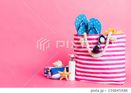 Stylish bag with beach accessories . Summer holiday concept. Top view of beach bag with sunscreen cream with space for text Stylish bag with beach accessories . Summer holiday concept. Top view of beach bag with sunscreen cream with space for text 139845486