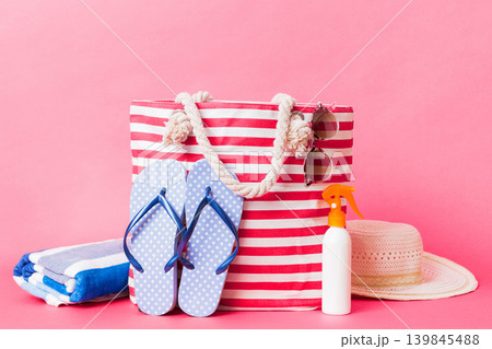 Stylish bag with beach accessories . Summer holiday concept. Top view of beach bag with sunscreen cream with space for text Stylish bag with beach accessories . Summer holiday concept. Top view of beach bag with sunscreen cream with space for text 139845488