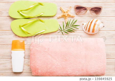 Summer holiday concept. Top view of beach towel, flip flop and sunscreen cream on table Top view with copy space for text Summer holiday concept. Top view of beach towel, flip flop and sunscreen cream on table Top view with copy space for text 139845925